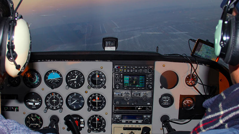 eine Cockpitansicht mit Funktionstafeln und zwei Piloten eines fliegenden Flugzeugs